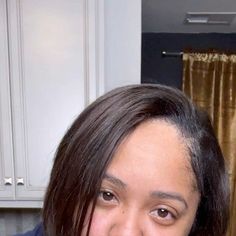 a young woman is smiling and wearing a blue shirt in the kitchen with gold curtains behind her