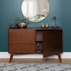 a wooden cabinet with two drawers and a round mirror on the wall above it in a living room