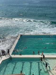 people are swimming in an outdoor pool next to the ocean