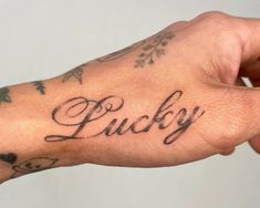 a person's hand with a tattoo on it that says lucky in cursive writing