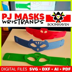 three different colored masks sitting on top of a table next to a computer screen with the words pj masks wristbands above them