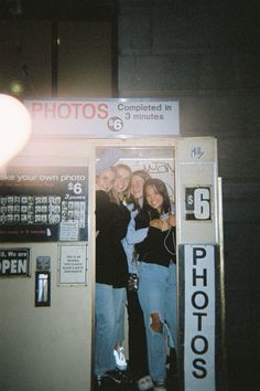 three women standing in front of a vending machine with their arms around each other