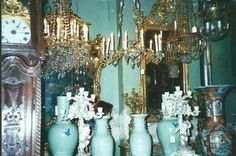 there are many vases on the table in front of a mirror with candles and chandelier