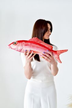 a woman holding a red fish in her hands