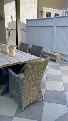 an outdoor table and chairs with potted plants on it