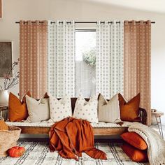 a living room filled with lots of pillows and blankets on top of a couch next to a window