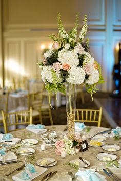 a vase filled with flowers sitting on top of a table next to plates and silverware