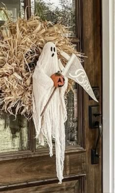 a door with a fake ghost hanging from it's side and a pumpkin in the front