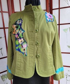 Celebrate the vibrancy of spring with this unique, one-of-a-kind jacket crafted from upcycled materials. Featuring a colorful floral design and green accents, this jacket is both stylish and eco-friendly. Size: 14 (per "Talbots" label) Measurements: * Shoulder to Shoulder: 15.5" * Sleeve Length: 23.5" * Pit to Pit: 21" * Length: 21" * Bottom Width: 42" Material:  Medium weight 96% cotton / 4% Spandex. Appliques are a cotton polyester blend. Details: * All pockets are working pockets. * Machine wash on delicate / dry on low. Some normal fraying may occur. Each piece is lovingly handcrafted, making it a truly unique addition to your wardrobe. Embrace your individuality and make a statement with this eye-catching jacket! Green Spring Outerwear With Buttons, Green Cotton Outerwear With Floral Embroidery, Fitted Green Cotton Outerwear, Fitted Green Outerwear For Spring, Spring Patchwork Outerwear, Green Summer Outerwear With Buttons, Spring Upcycled Long Sleeve Outerwear, Upcycled Long Sleeve Outerwear For Spring, Spring Multicolor Floral Patchwork Outerwear