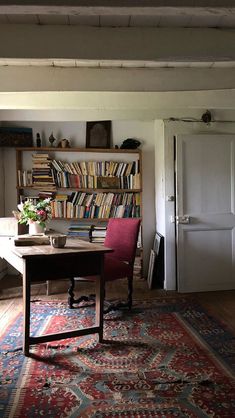 a room with a table, chair and bookshelf filled with lots of books