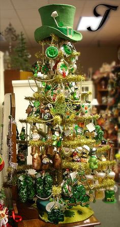 a christmas tree decorated with green and gold ornaments in a store display case, surrounded by other holiday decorations