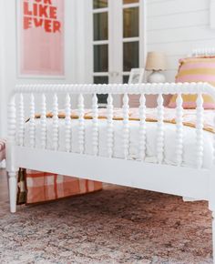 a white bed sitting on top of a wooden floor next to a pink and white rug