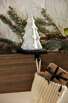 a small white christmas tree sitting on top of a wooden shelf next to a brown box