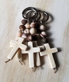 a cross keychain sitting on top of a wooden table next to beads and rings