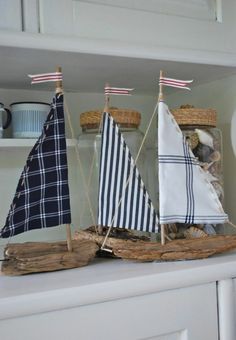 a white shelf topped with wooden boats on top of each other next to a blue and white flag