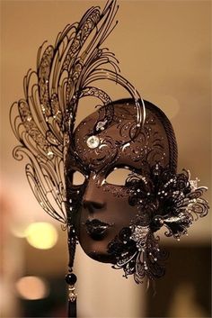 a black mask with feathers and jewels on it