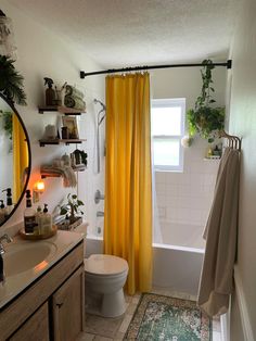 a bathroom with yellow shower curtains and plants on the shelf next to the bathtub