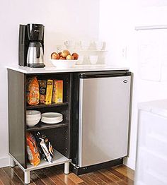 a small refrigerator in a kitchen next to a counter with food and drinks on it