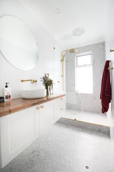 a bathroom with a sink, mirror and bathtub next to a window in it