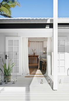 an open door to a white house with a potted plant on the porch next to it