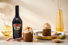 there is a bottle of bailey's irish cream next to two cups of hot chocolate