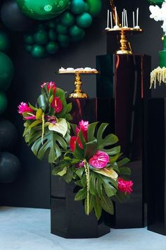 three black vases with flowers in them on a table