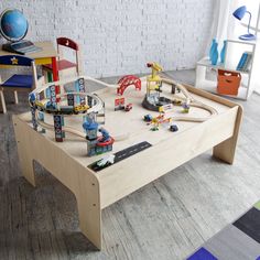 a child's wooden table with toys on it in a playroom area, including a train set