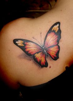 a colorful butterfly tattoo on the back of a woman's shoulder