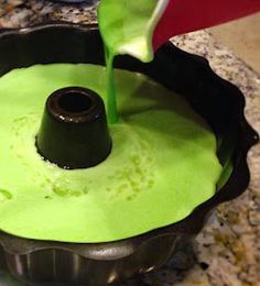 someone pouring green liquid into a cake pan