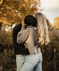 a man and woman embracing each other in front of trees