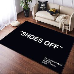 a black rug with the words shoes off on it in front of a white couch