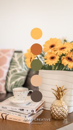 a table topped with books and a pineapple next to a vase filled with yellow flowers