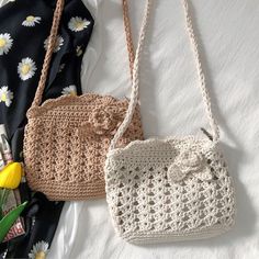 two crocheted purses sitting next to each other on a white sheet with flowers