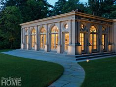 a large white building sitting in the middle of a lush green park at night time