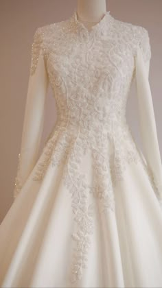 a white wedding dress with long sleeves and beading on the neckline is displayed