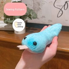 a hand holding a small blue stuffed animal