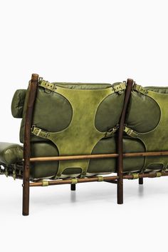 a green leather couch sitting on top of a wooden frame