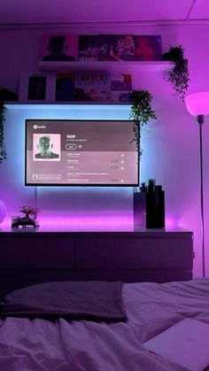 a bedroom with purple lighting and a flat screen tv mounted on the wall above it