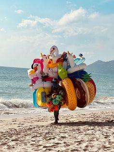 a person on the beach with an inflatable toy and other items attached to his back