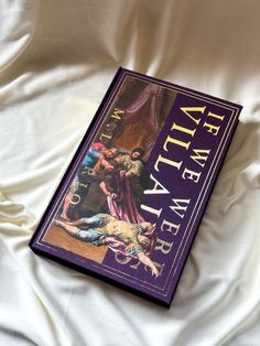 a purple book sitting on top of a white bed covered in sheets and blankets,