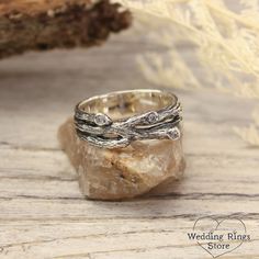 a silver ring sitting on top of a rock next to a piece of driftwood