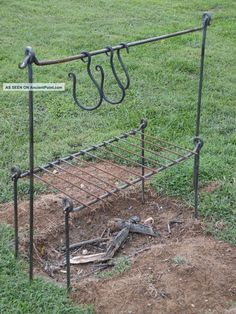 an old iron bed frame is in the middle of a field with grass and dirt