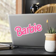 a laptop computer sitting on top of a wooden desk next to a potted plant