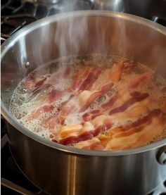 bacon is being cooked in a pan on the stove top with boiling water over it