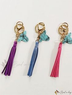 three key chains with tassels and charms on them