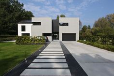 a modern house with white walls and black garage doors on the front entrance to it