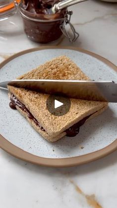 a sandwich cut in half on a plate with a knife sticking out of the top