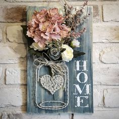 a mason jar filled with flowers sitting on top of a wooden wall hanging sign that says home