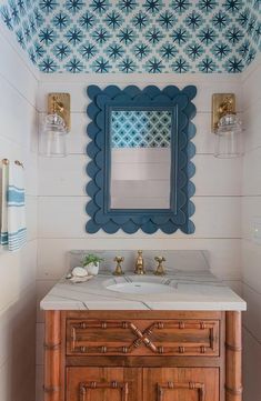 a bathroom with a sink, mirror and blue accents on the wall above it's counter