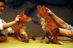 two people are playing with stuffed animals on a table